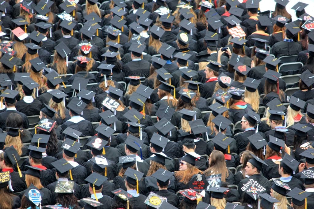 Students sitting together at graduation ceremony wearing caps and gowns